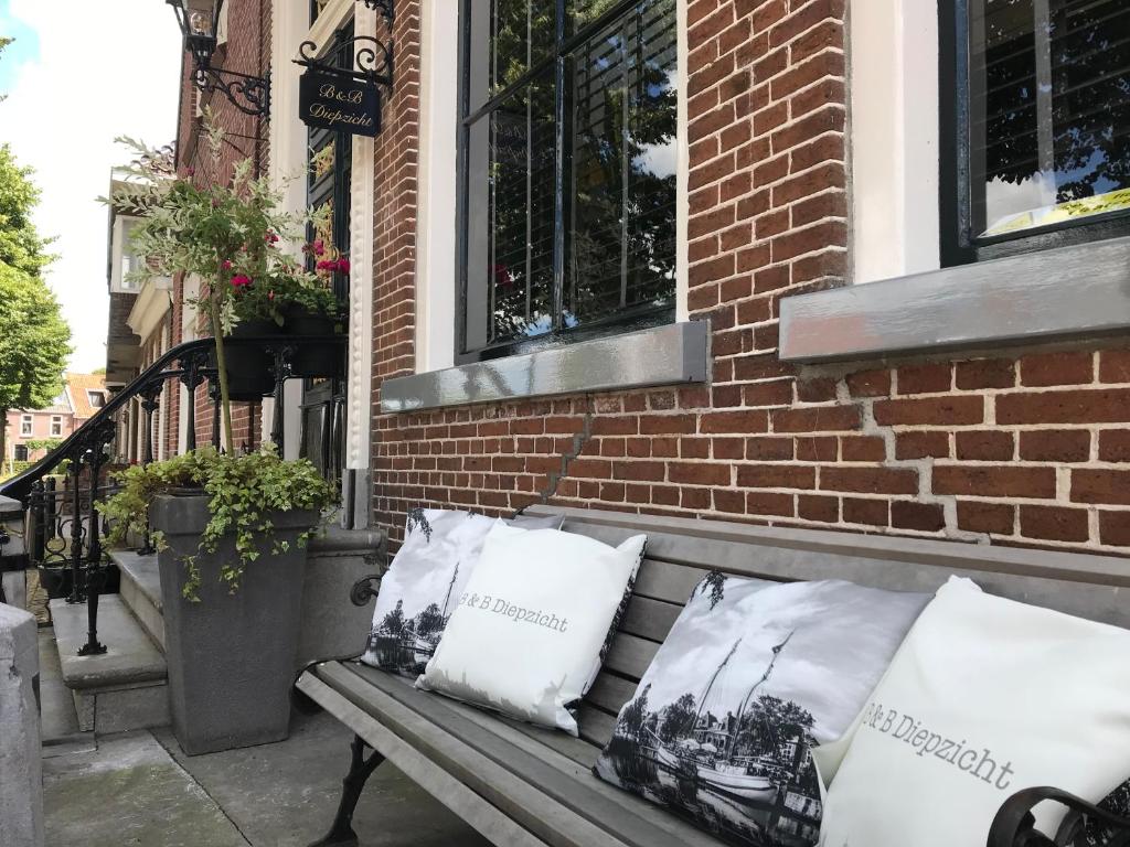 a bench sitting outside of a brick building with pillows at B&B Diepzicht in Dokkum