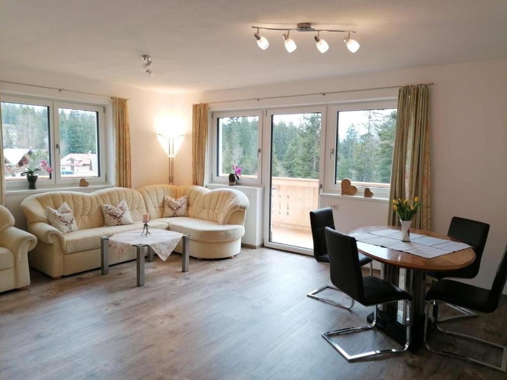 ein Wohnzimmer mit Sofas, Tischen und Fenstern in der Unterkunft Appartement Kaiserplatzl in Scheffau am Wilden Kaiser