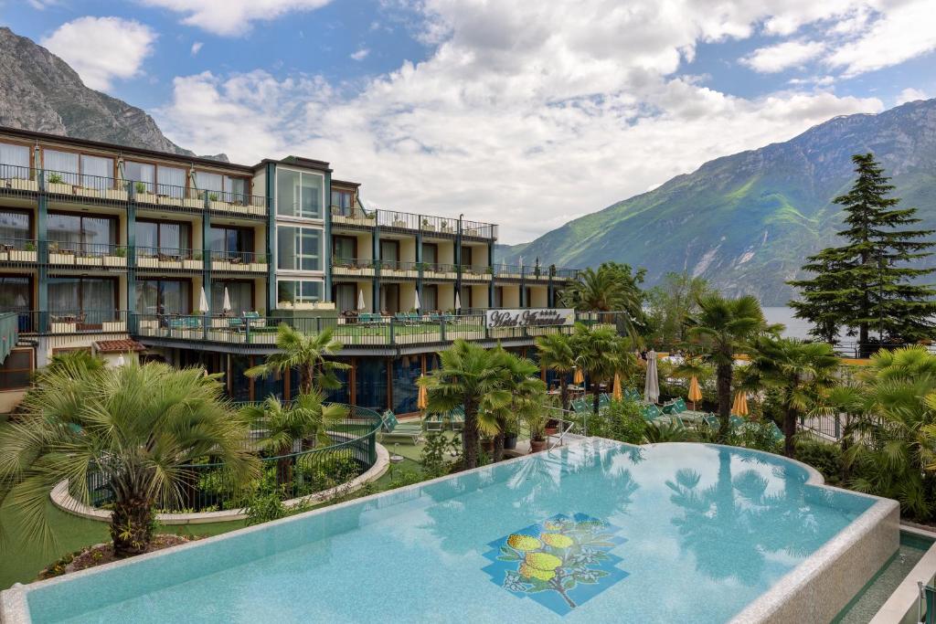 un resort con piscina e montagne sullo sfondo di Hotel Alexander a Limone sul Garda