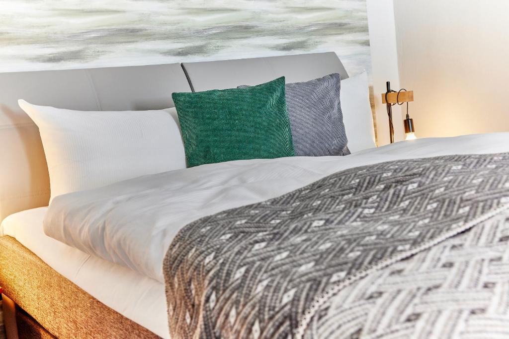 a bedroom with a large white bed with green pillows at Schlei Hotel in Kappeln