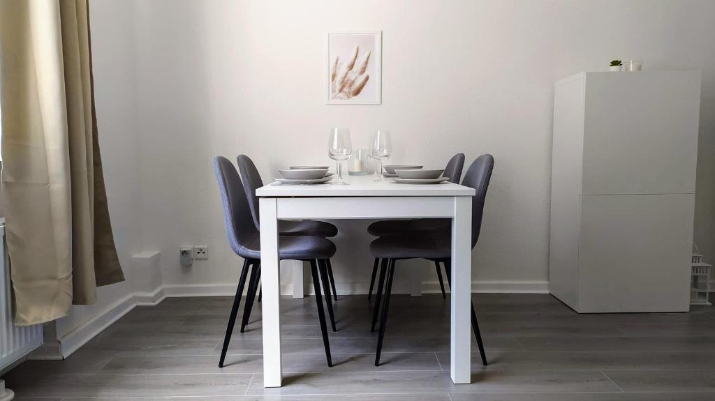 - une table blanche avec des chaises et des verres à vin dans l'établissement Moderne City Apartments im Stadtzentrum, à Kiel