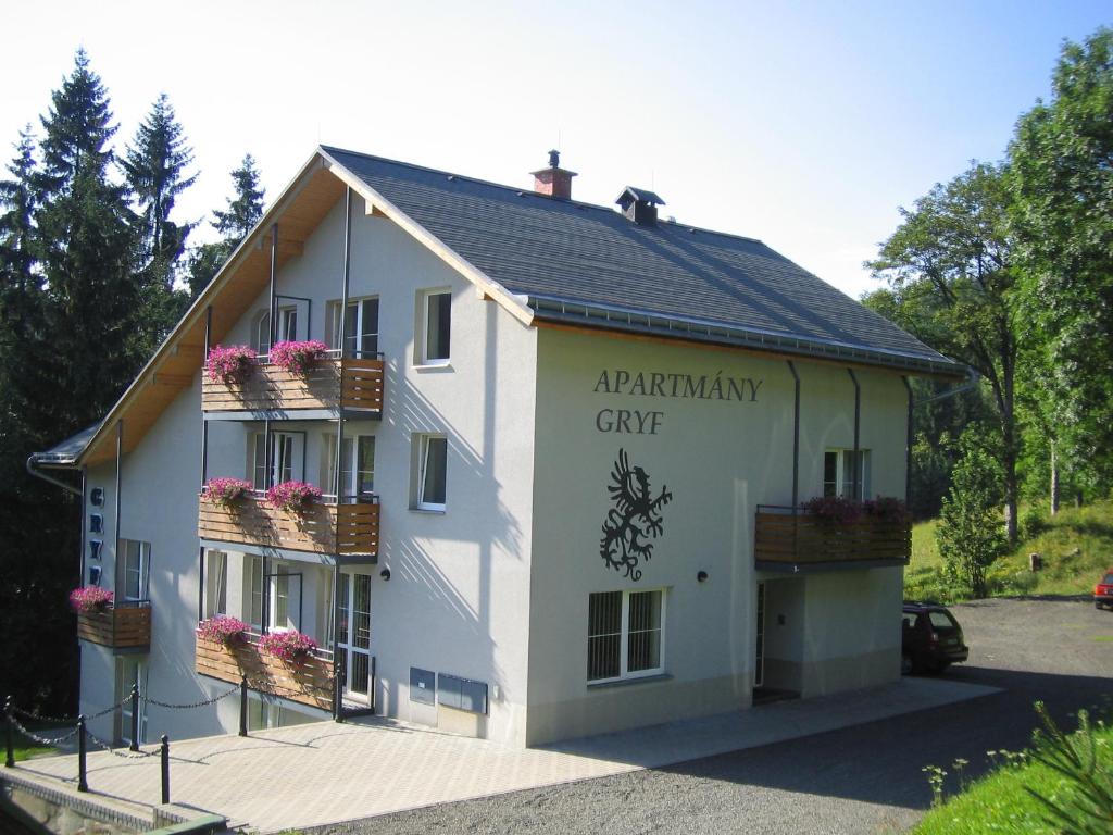 un edificio blanco con flores en las ventanas en Apartmány Gryf Harrachov, en Harrachov