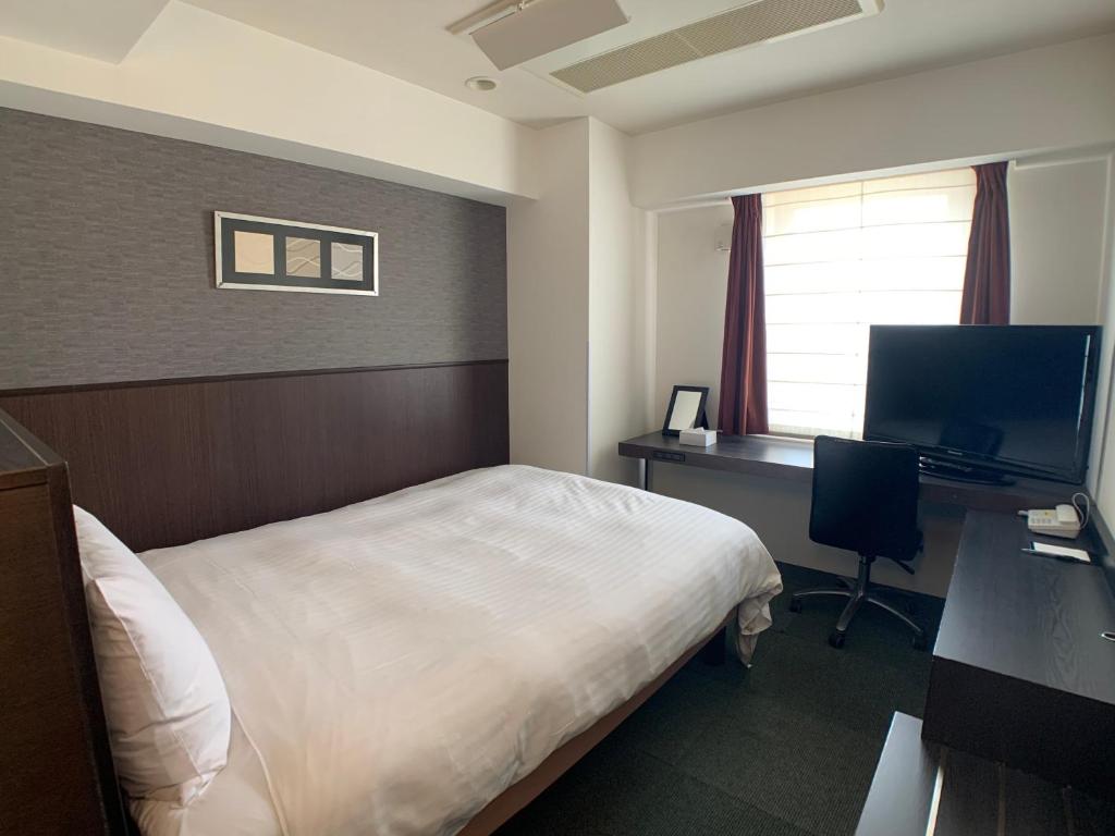 a hotel room with a bed and a desk with a computer at Smile Hotel Nagoya Sakae in Nagoya