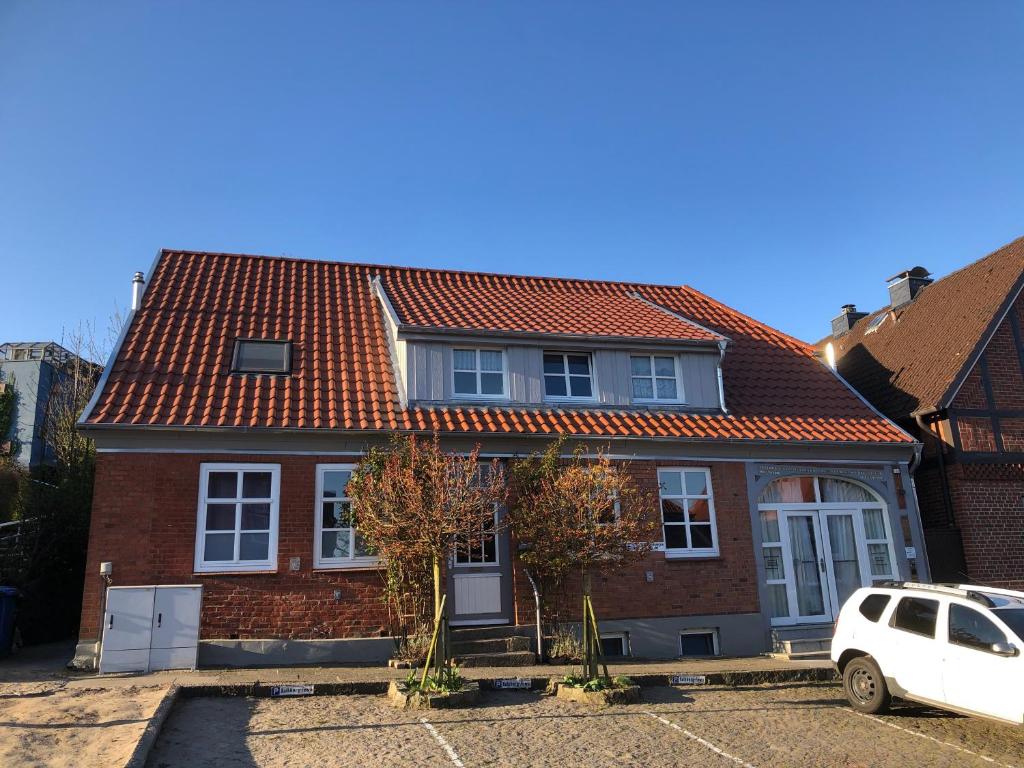 een huis met rode daken en een witte auto voor de deur bij Kalkberg Ferienwohnungen in Bad Segeberg