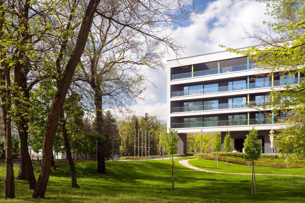 an office building in a park with trees at Hunguest Hotel Sóstó in Nyíregyháza