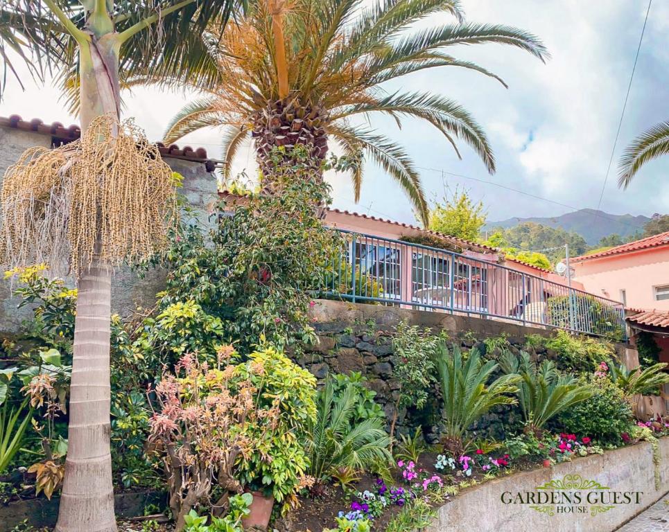 un palmier et des fleurs devant un bâtiment dans l'établissement Gardens Guest House, à São Vicente