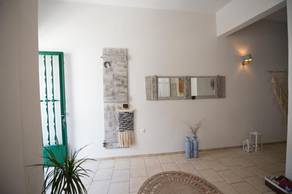 a room with a white wall with a mirror and a rug at Art apartment in Ancient Epidavros