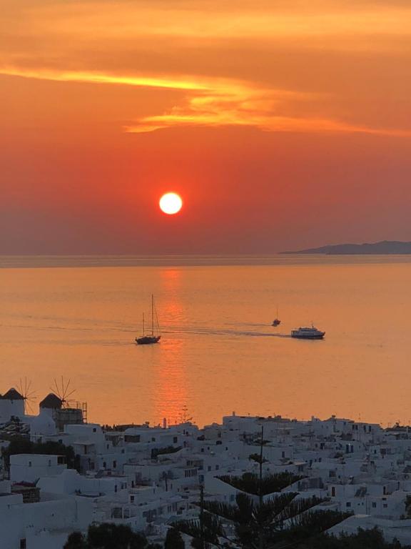 een zonsondergang over de oceaan met boten in het water bij Ibiscus Boutique in Mykonos-stad