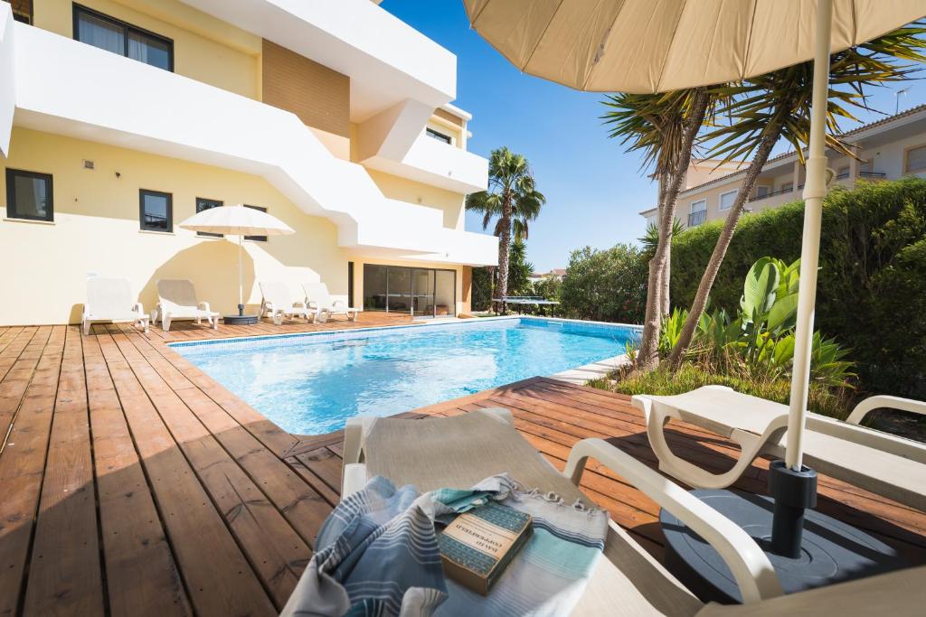 - une piscine avec des chaises et un parasol à côté d'un bâtiment dans l'établissement Villa Boho, à Lagos