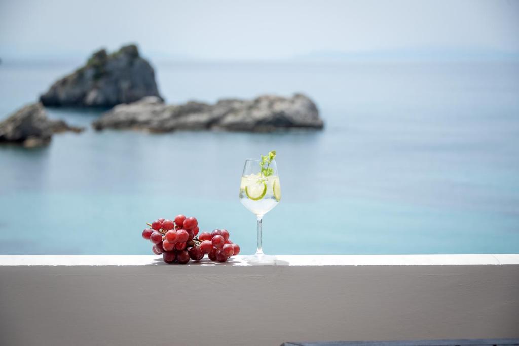 een glas wijn en druiven op een tafel voor de oceaan bij Krioneri Beach in Parga