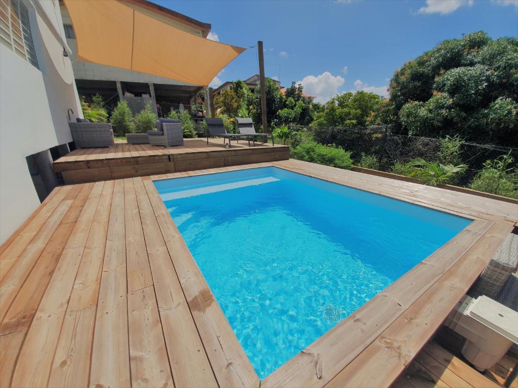 una piscina con terrazza in legno accanto a una casa di Kozycoco - Suite Kozy - séjour tropical au calme a Schœlcher