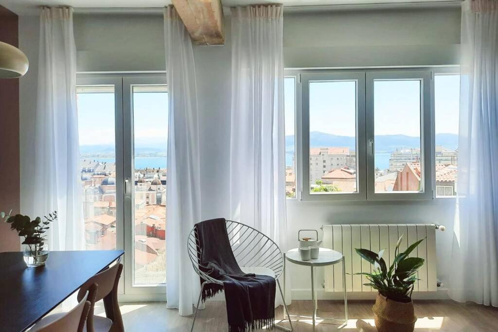 een eetkamer met een tafel en ramen met uitzicht bij Céntrico piso reformado con vistas a la Bahía in Santander