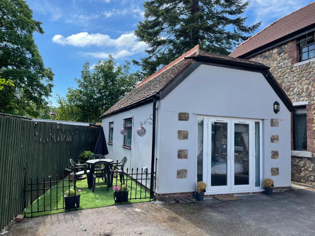 ein kleines weißes Cottage mit einem Tisch und einem Zaun in der Unterkunft Ty Mynydd Lodge Holiday Home in Cardiff