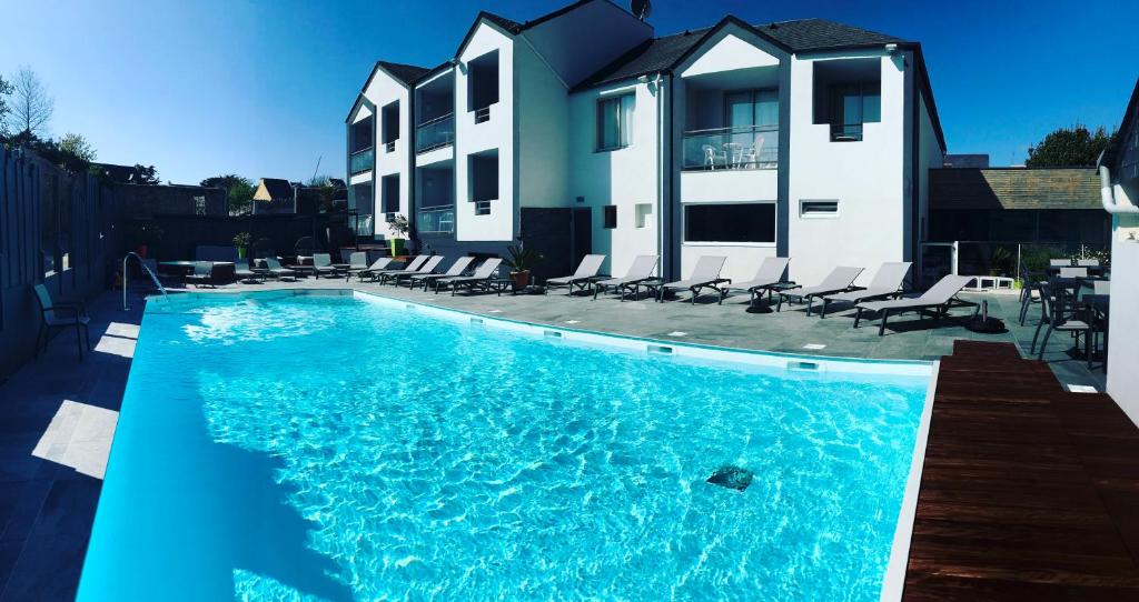 a swimming pool with chairs in front of a house at Le Thalassa Hôtel & Spa in Camaret-sur-Mer