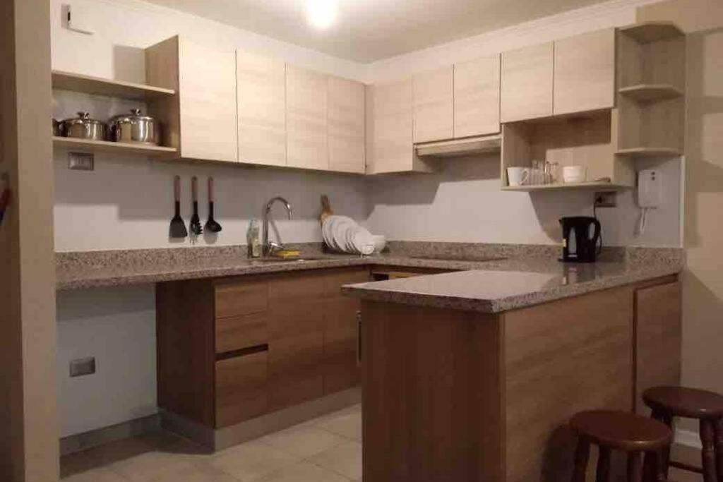 una cocina con armarios blancos y una barra con taburetes en Acogedor depto en barrio residencial, La Serena, en La Serena