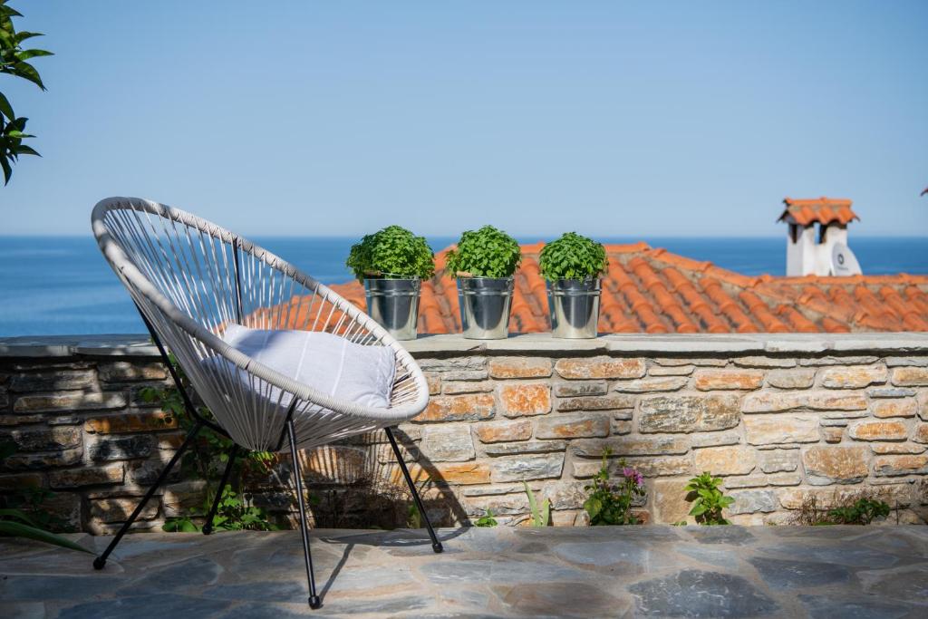 uma cadeira branca sentada em cima de uma parede de tijolos em Aegean Blue - Villas Stivachtis em Agios Ioannis Pelio