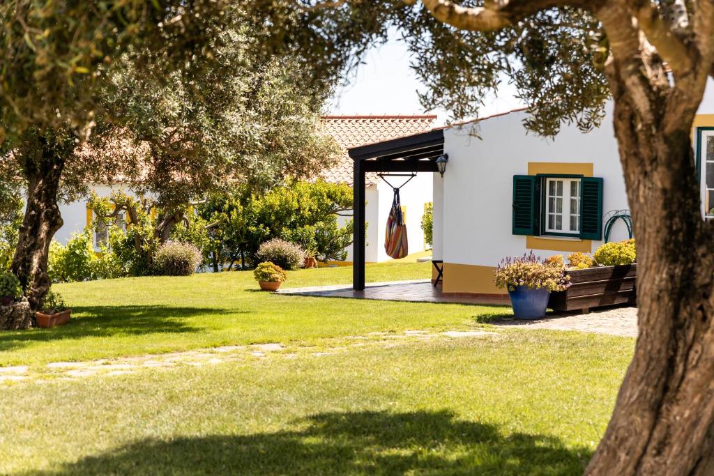 een tuin met een wit huis met een groene luik bij Monte Das Alpenduradas in Zambujeira do Mar