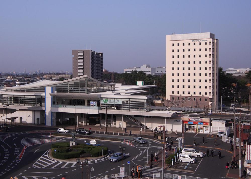 een stad met een gebouw en een straat met auto's bij Life Inn Katsuta Station West in Hitachinaka