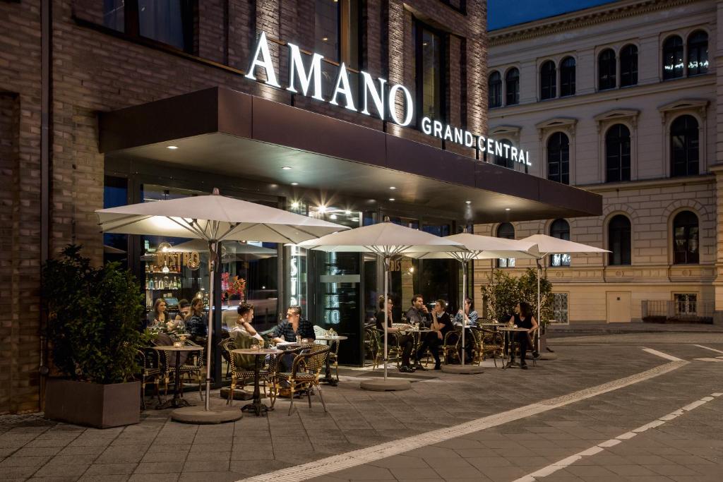 un groupe de personnes assises à des tables à l'extérieur d'un restaurant dans l'établissement Hotel AMANO Grand Central, à Berlin