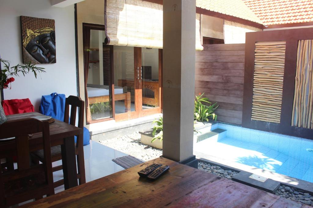 a living room with a table and a swimming pool at Jukung Villas Kuta in Kuta