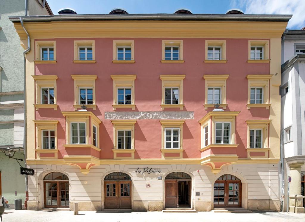 un bâtiment rose et jaune dans une ville dans l'établissement Altstadthotel der Patrizier, à Ratisbonne