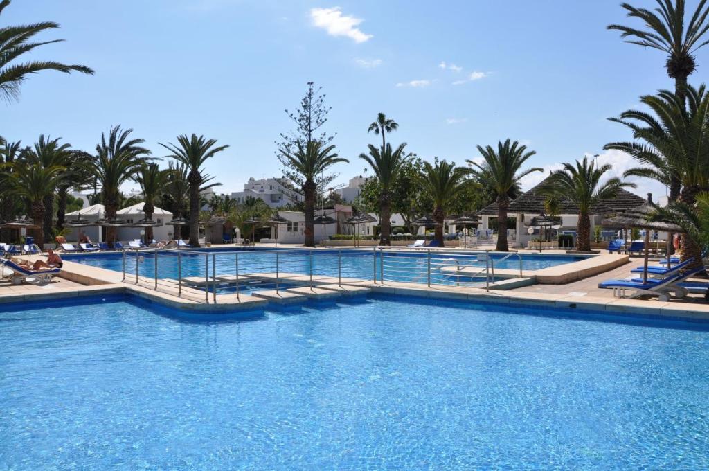 una piscina in un resort con palme di Kanta Resort and Spa a Sousse