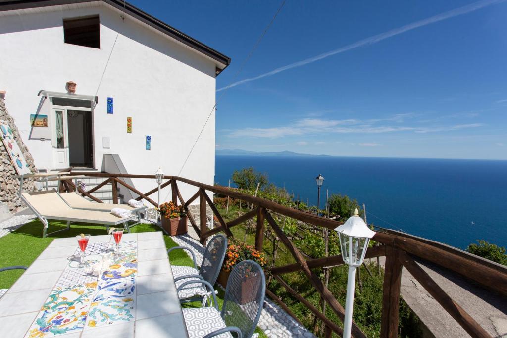 un tavolo e sedie su un balcone con vista sull'oceano di Holidays Perla d'Amalfi ad Amalfi