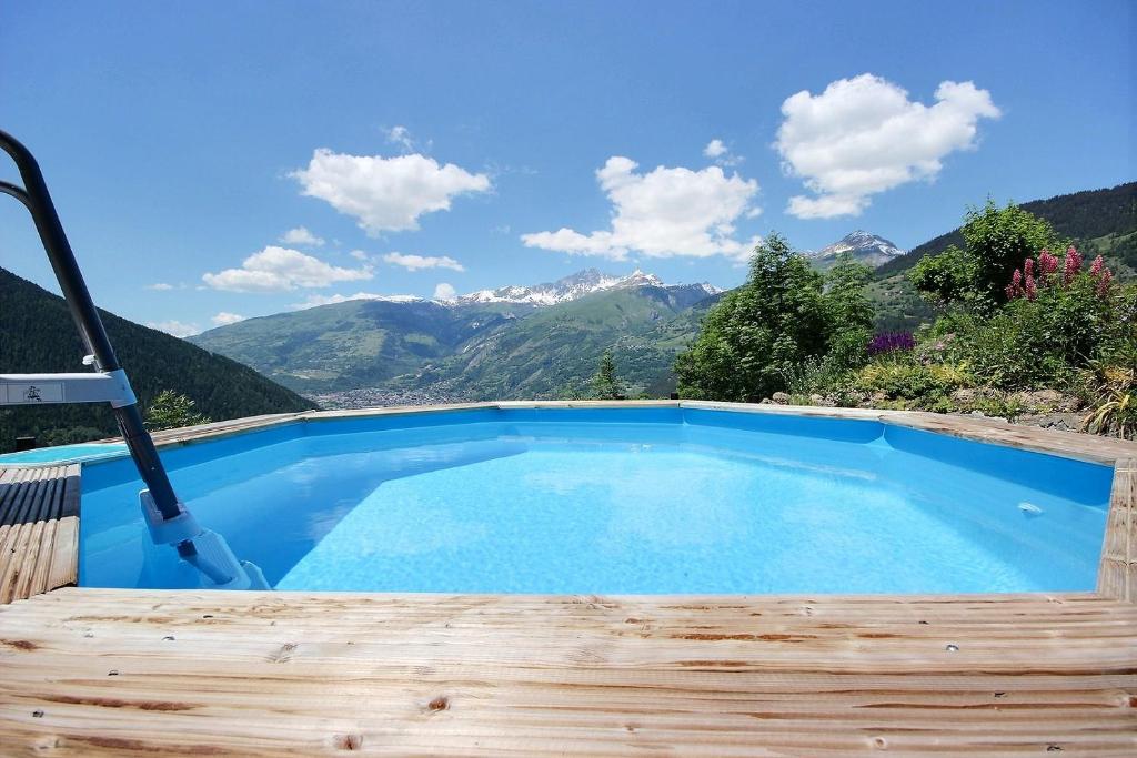 a blue swimming pool with mountains in the background at Les Balcons du Molliebon in Séez