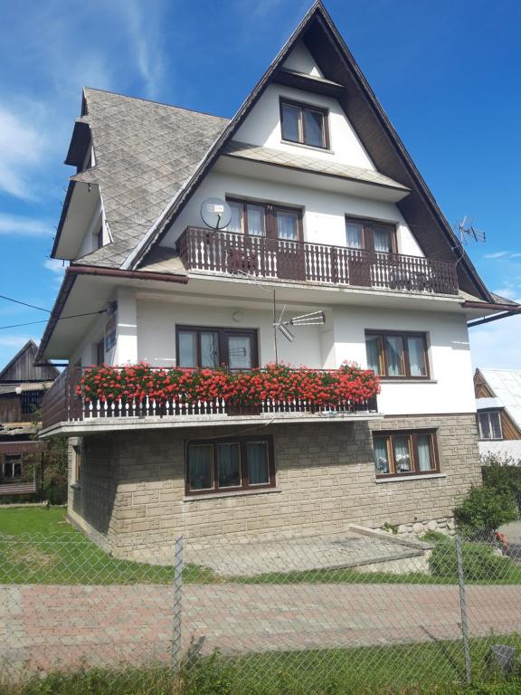 a house with red flowers on the balcony at Pod Tatarską Górą in Biały Dunajec