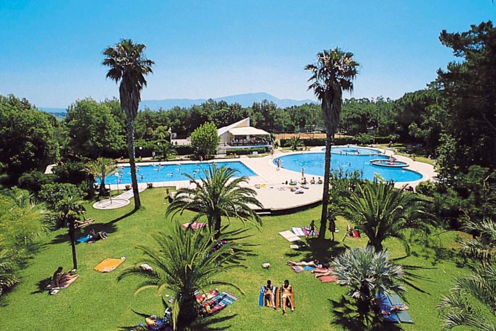 un resort con una grande piscina con palme di Happy Camp mobile homes in Villaggio Camping Baia Domizia a Baia Domizia