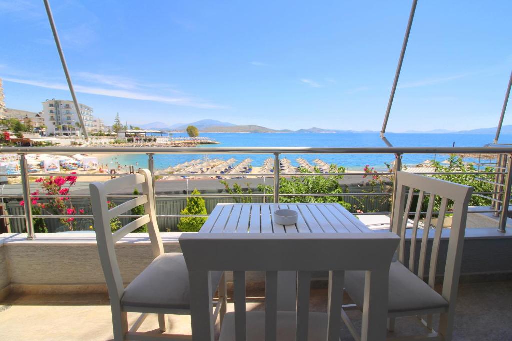 un tavolo e sedie su un balcone con vista sulla spiaggia di Zero Zero Apartments Sarande a Sarandë