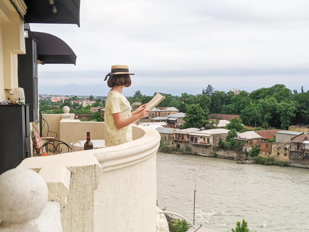 Una donna che si trova su un cornicione e guarda verso un fiume di Boutique Apartment - Signature a Kutaisi