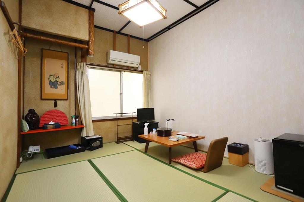 een kamer met een bureau, een tafel en een raam bij Hinode Ryokan in Ise