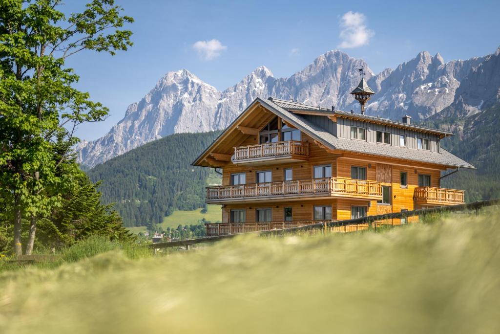 drewniany dom na wzgórzu z górami w tle w obiekcie Alpin Residenz Dachsteinperle w mieście Ramsau am Dachstein