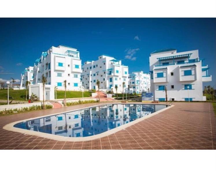 Smir Park appartement Haut standing Marina Smir في مارينا سمير: مسبح امام بعض المباني البيضاء