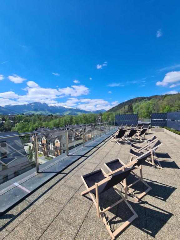 une rangée de bancs en bois assis au-dessus d'un toit dans l'établissement Szklane Domy, à Zakopane