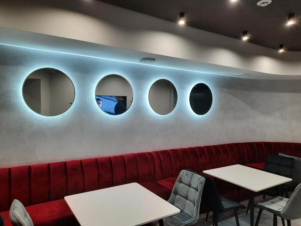 a restaurant with a red couch and four circular windows at Red Cube Hotel in Kamianets-Podilskyi