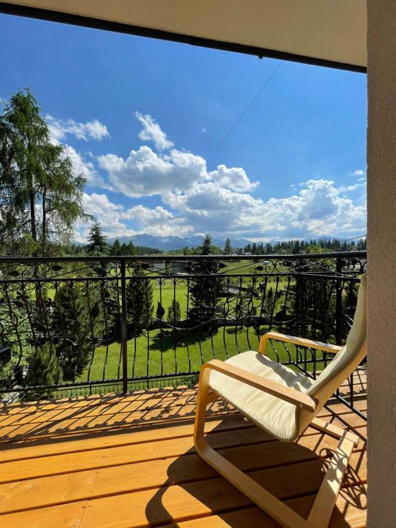 une chaise assise sur une terrasse avec vue sur un champ dans l'établissement Pokoje Gościnne MAGNAS, à Poronin