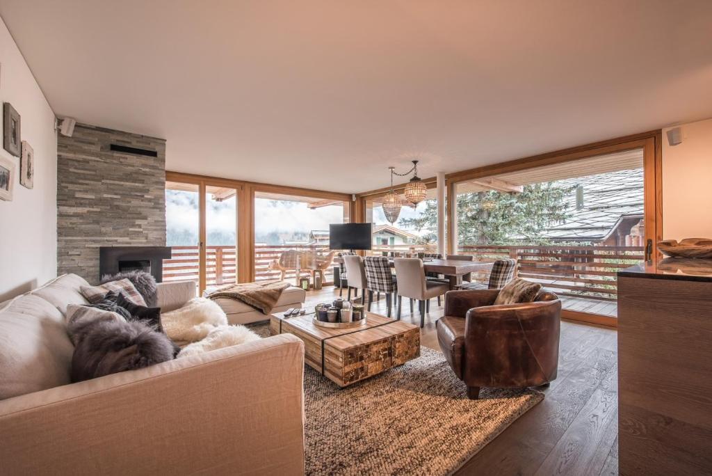 ein Wohnzimmer mit einem Sofa, Stühlen und einem Kamin in der Unterkunft Bergwelt Grindelwald Residence in Grindelwald