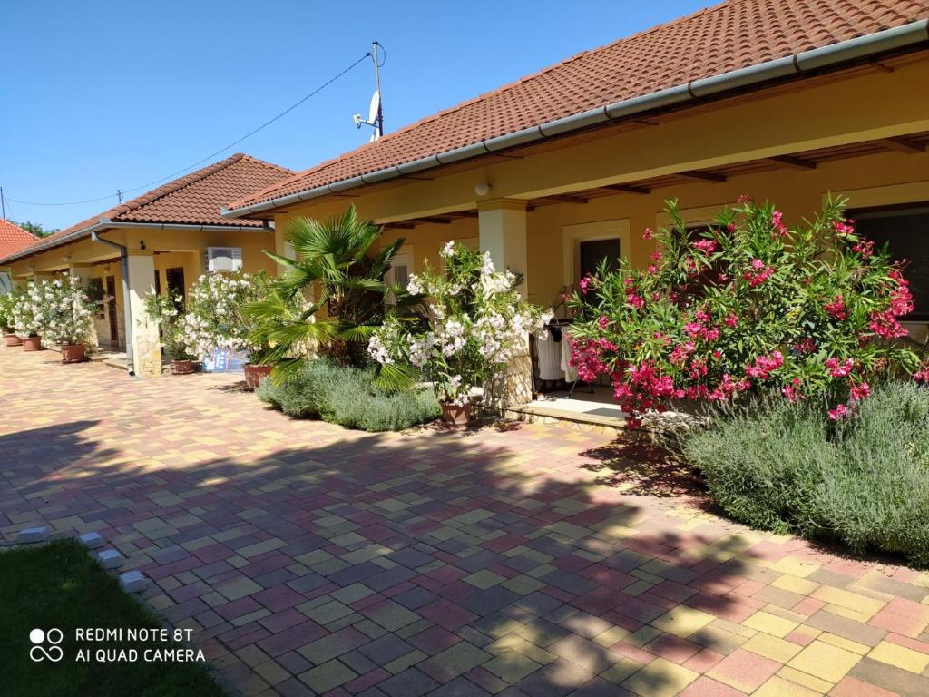 ein Haus mit Blumen und Pflanzen davor in der Unterkunft Spengler Apartman in Harkány