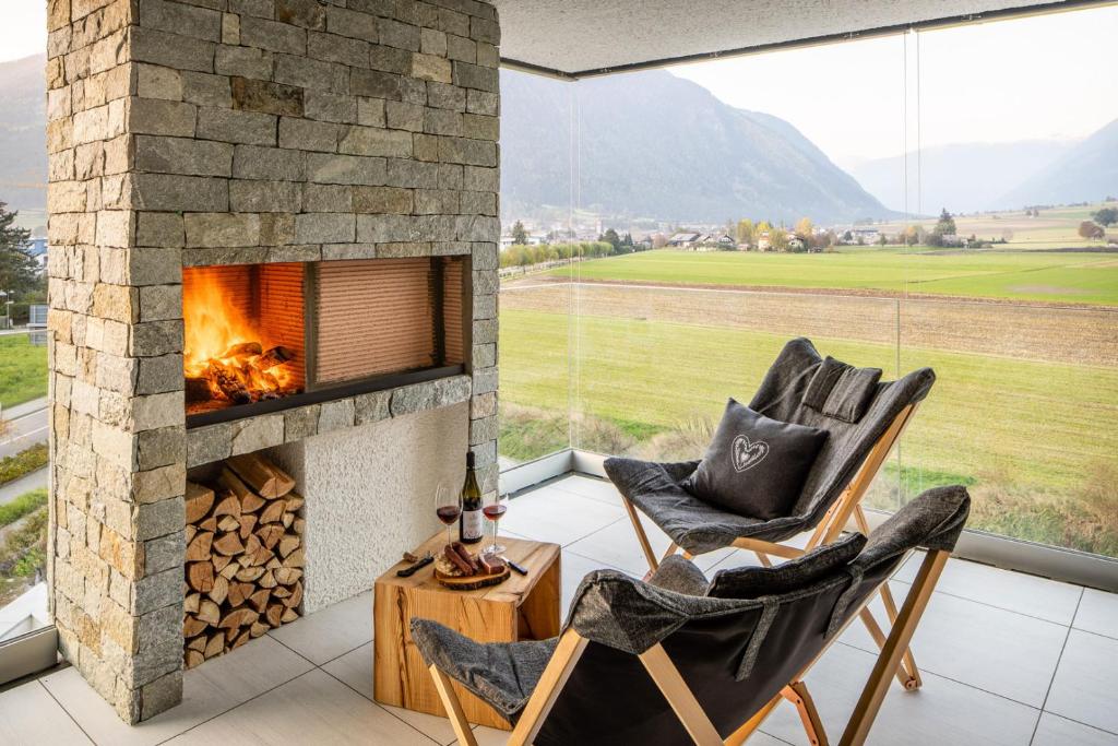 un camino in un soggiorno con due sedie di Bellevue Bruneck - Suites & Lofts a Brunico