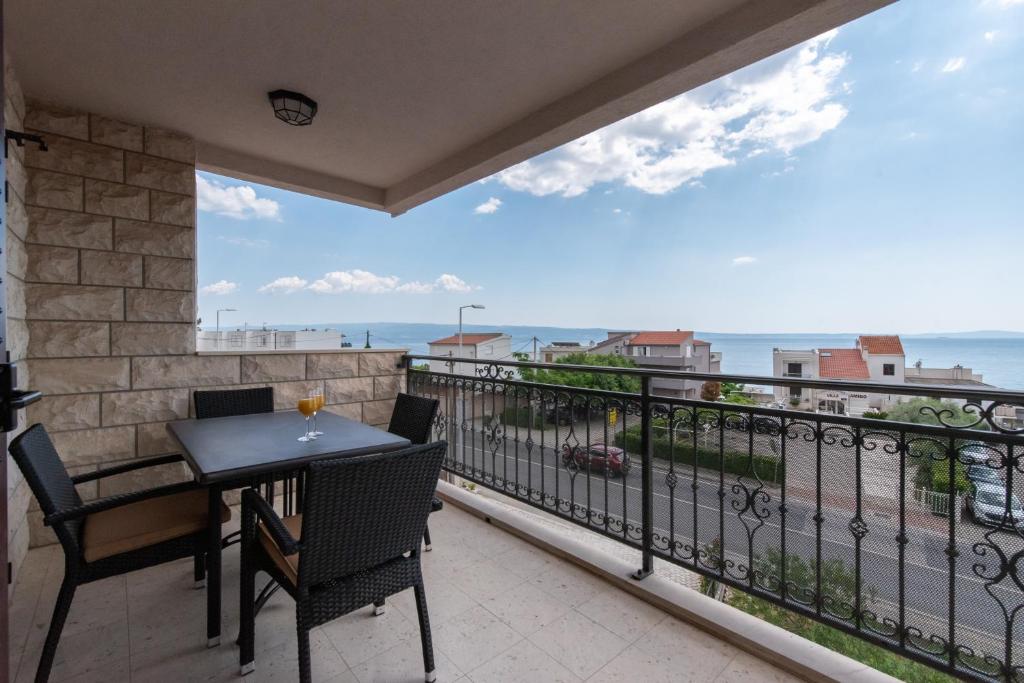 d'un balcon avec une table et des chaises et une vue sur l'océan. dans l'établissement Apartments Amigos, à Podstrana