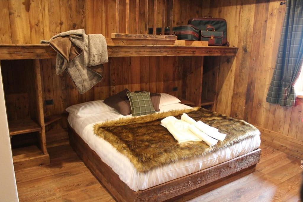 1 dormitorio con 1 cama en una pared de madera en FORESCH HUS CHAMBRES D'HOTES, en Gressoney-Saint-Jean