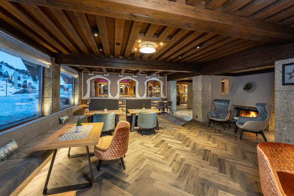 a lobby with tables and chairs and a fireplace at Hotel Alpina in Obertauern