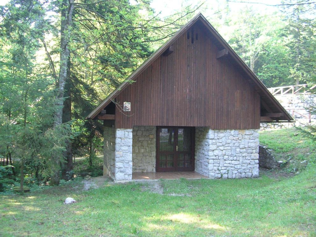 een klein stenen en houten gebouw in het gras bij Camping Pivka Jama Postojna in Postojna