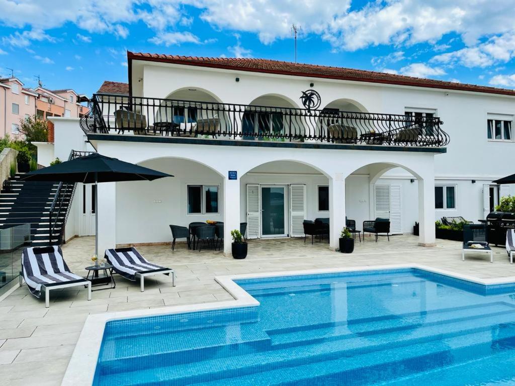 una villa con piscina di fronte a una casa di Villa Gala a Trogir