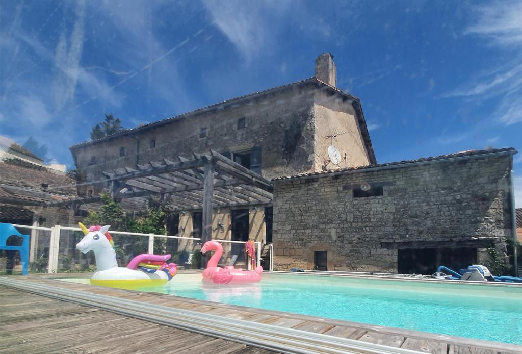 zwei aufblasbare Flamingos in einem Pool neben einem Gebäude in der Unterkunft Maison Fossemagne in Melle