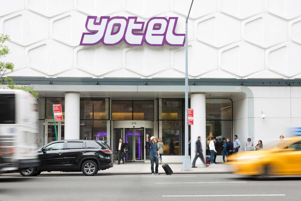 Um homem está a andar em frente a uma loja. em YOTEL New York Times Square em Nova Iorque