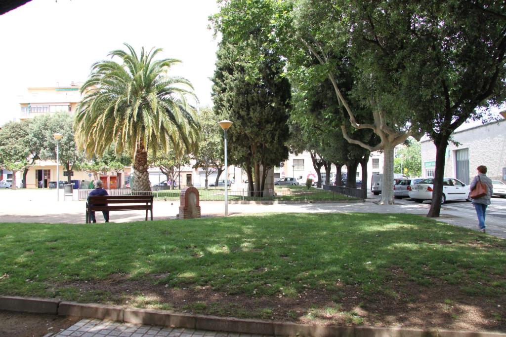 a person sitting on a bench in a park at Apartaments Centre Figueres in Figueres