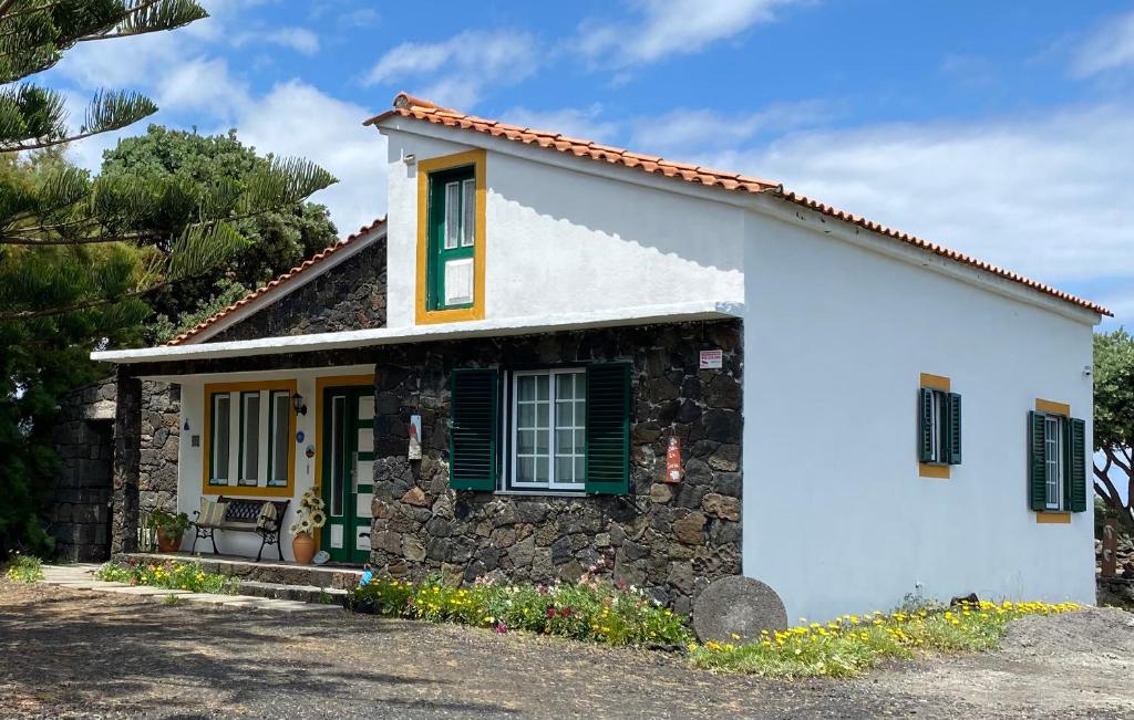 una pequeña casa blanca con persianas verdes en Casa da Costa, en Madalena